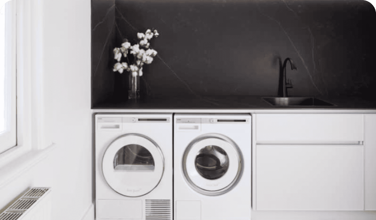 Clean laundry room with white machines and storage cabinets